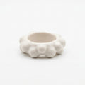 Burbuja — anillo de porcelana blanca con fila de esferas sobre fondo blanco, vista frontal