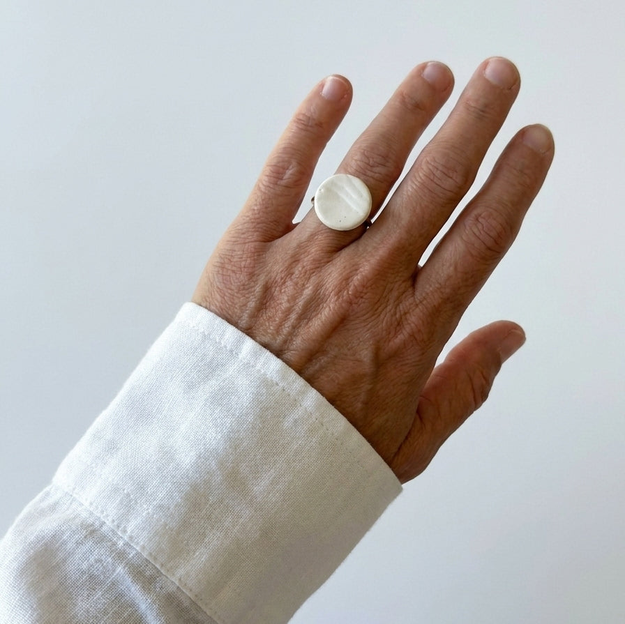 Marea Baja — anillo de porcelana blanca en mano con camisa blanca
