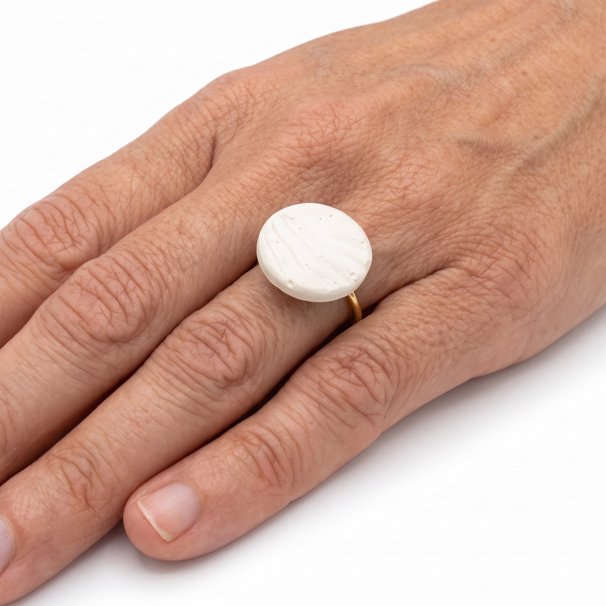 Marea Baja — anillo de porcelana blanca con surcos en mano, fondo blanco