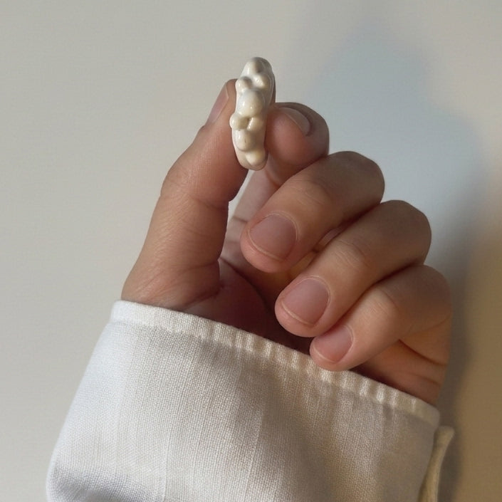 Burbuja — anillo de porcelana blanca con fila de esferas en dedo índice, vista lateral