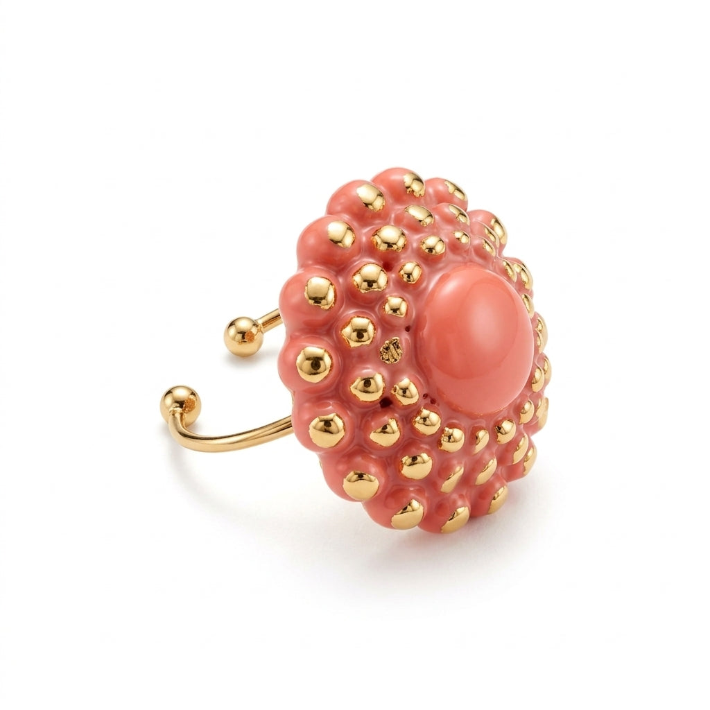 Girándola Coral — vista lateral del anillo de porcelana coral con aro abierto regulable dorado con remates en bola, sobre fondo blanco