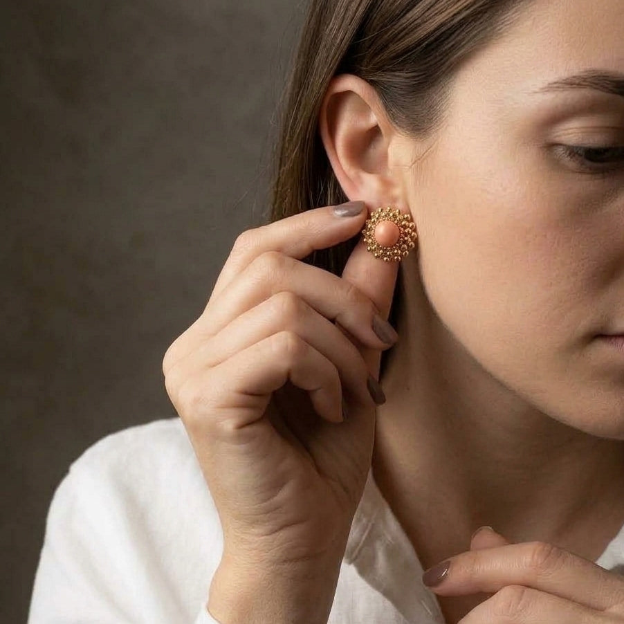 Pendientes Girándola Rosa Palo — mujer colocando pendiente stud de porcelana rosa con bultos dorados, camisa blanca, fondo gris oscuro