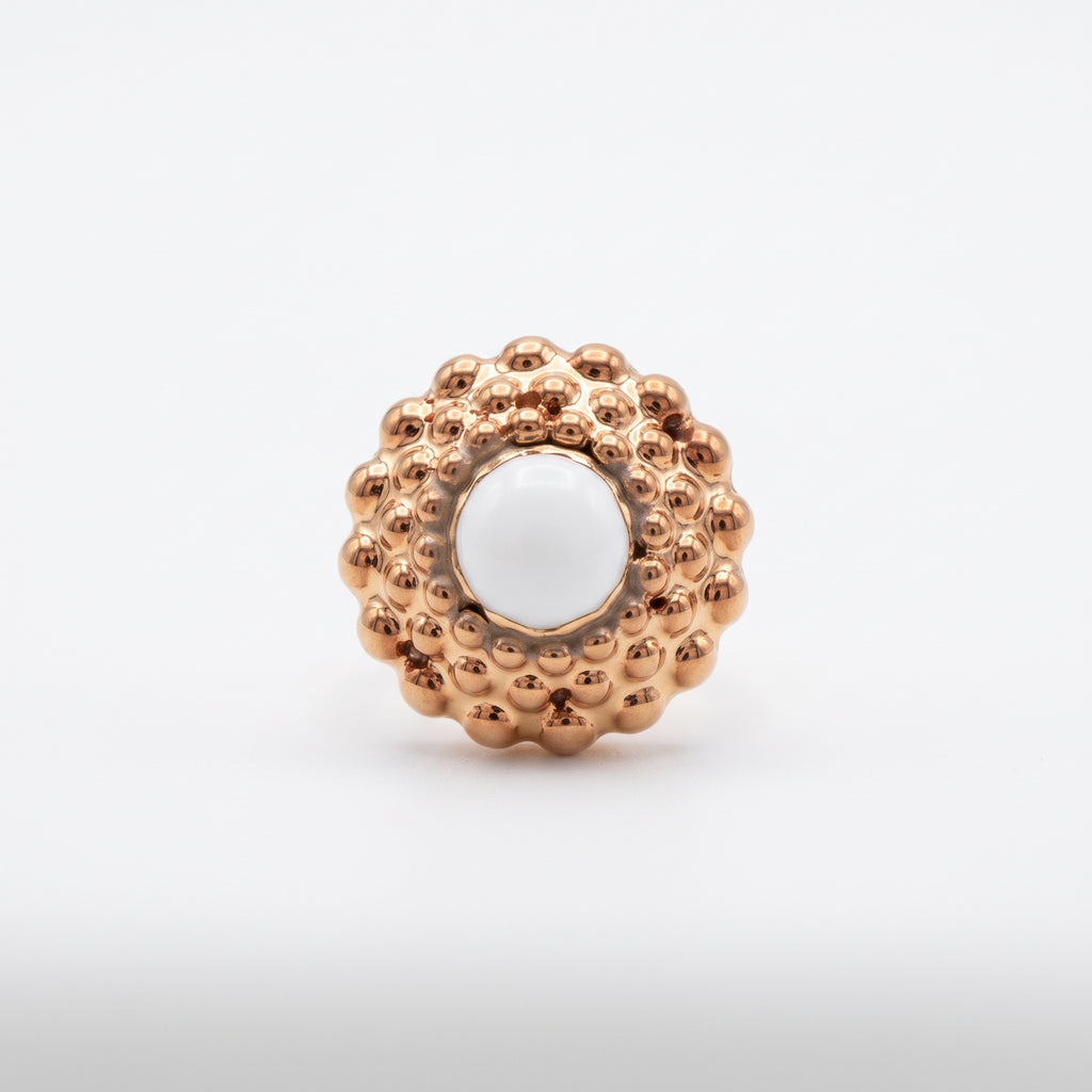Girándola Amanecer — vista frontal del anillo de porcelana oro rosado con bultos dorados y centro blanco nacarado, fondo blanco