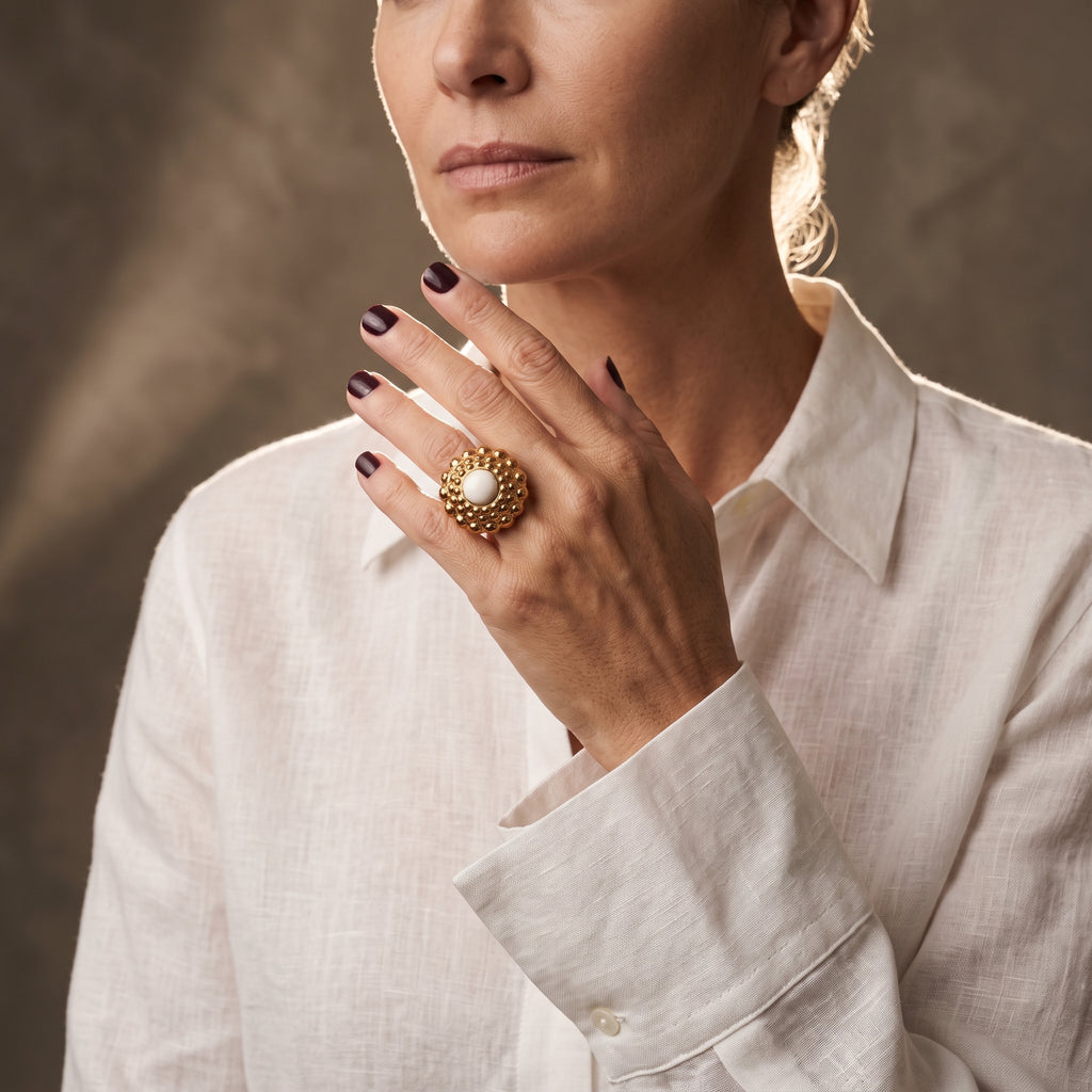 Girándola Amanecer — modelo con camisa blanca y el anillo dorado rosado en el índice, fondo beige cálido con luz suave