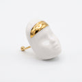 Domina — vista lateral del anillo escultórico de porcelana blanca con rostro y franja dorada en la frente, aro dorado abierto, fondo blanco