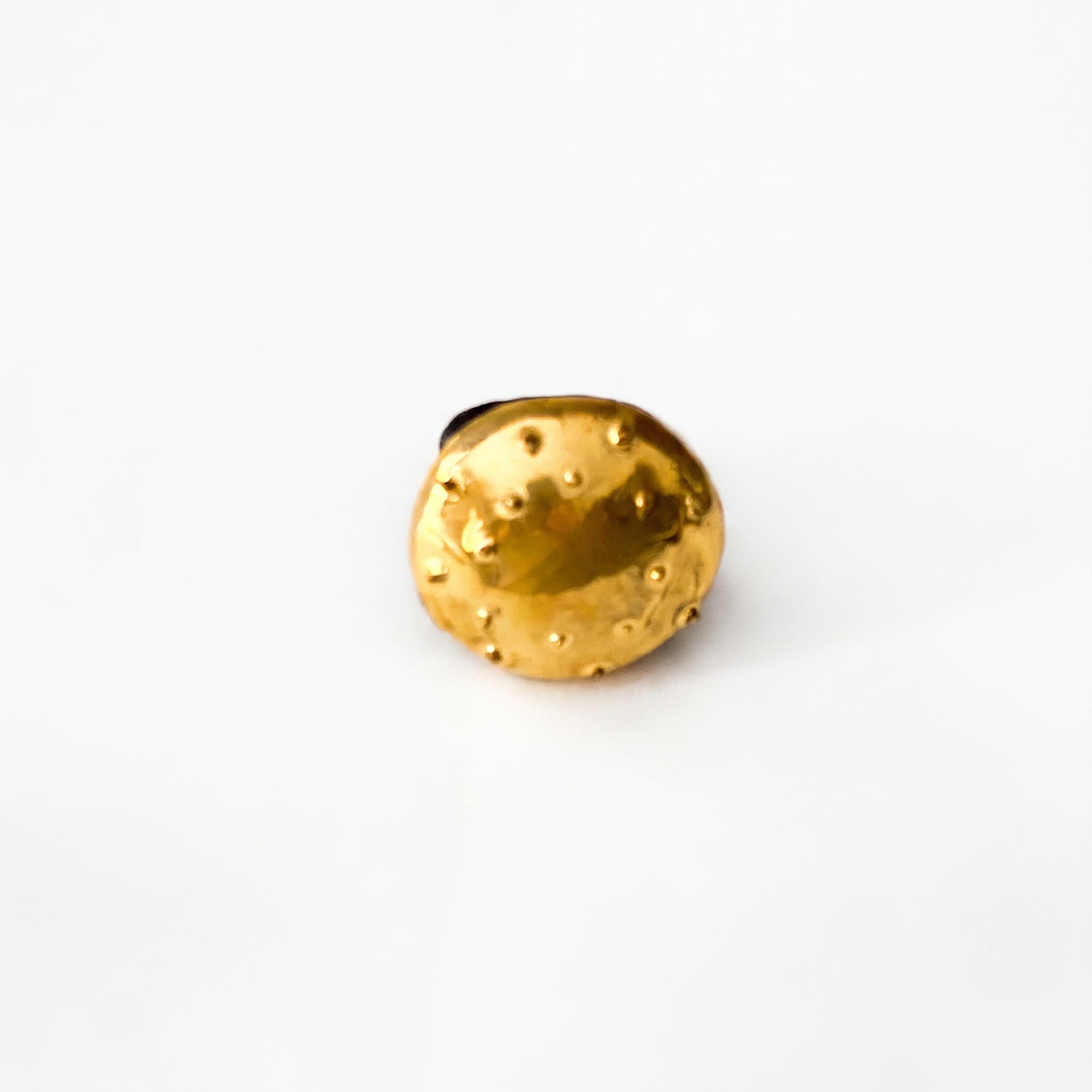 Erizo Dorado — anillo de porcelana con cúpula dorada y púas esféricas distribuidas, vista cenital sobre fondo blanco mostrando la textura completa