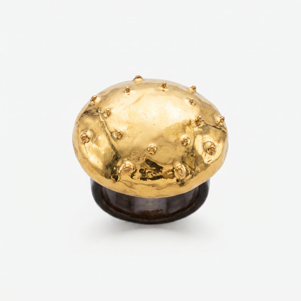 Erizo Dorado — anillo de porcelana con cúpula dorada y púas esféricas sobre base negra mate, vista frontal sobre fondo blanco mostrando el contraste oro y negro