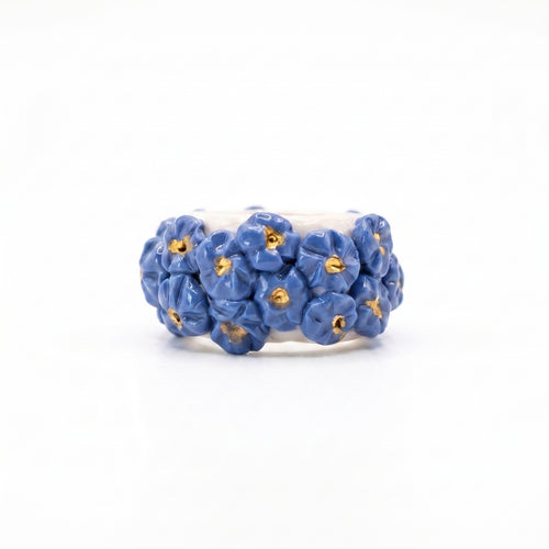Bouquet Azul — anillo de porcelana con flores azul aciano modeladas a mano y pistilos de oro, vista frontal sobre fondo blanco
