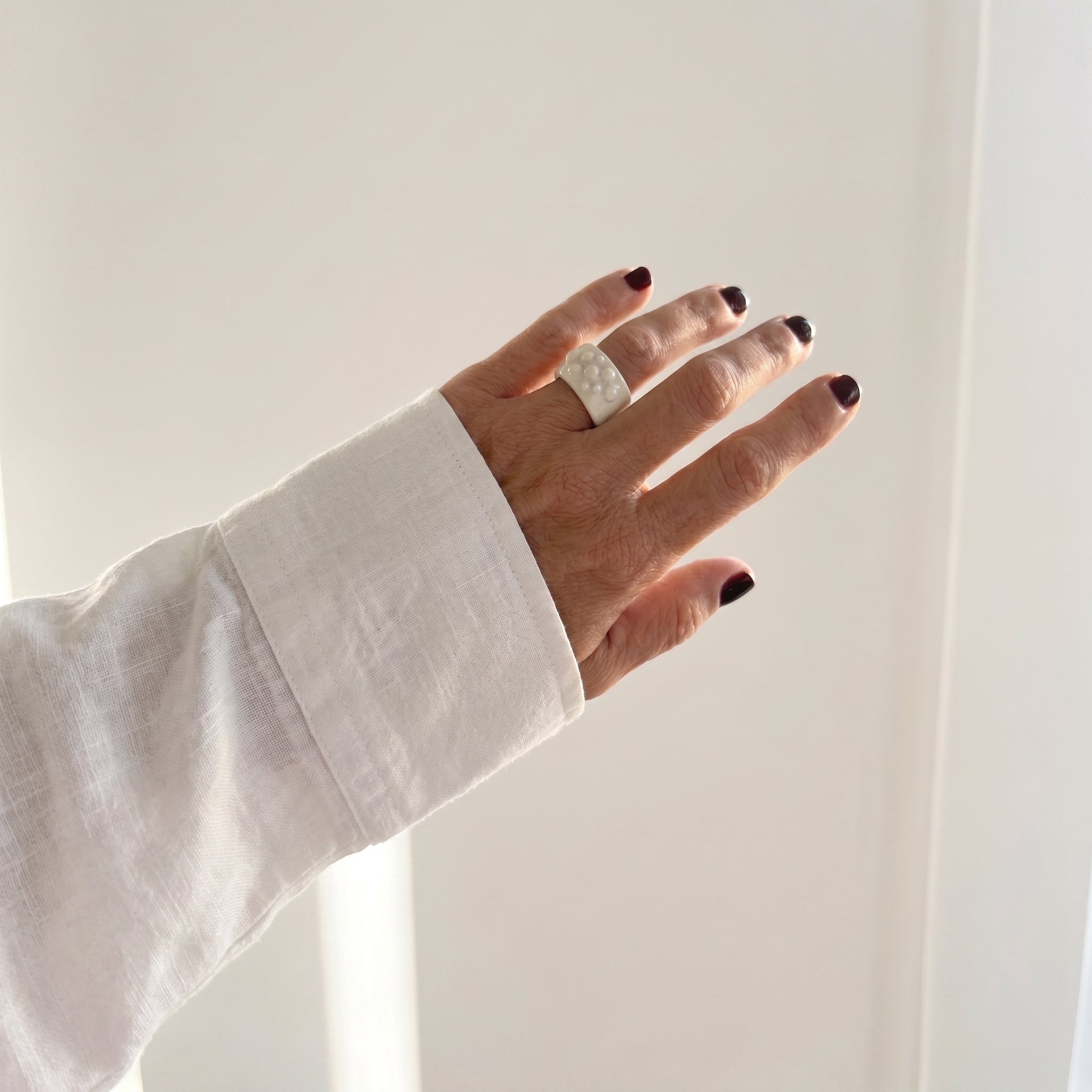 Bulla — anillo de porcelana blanca en mano con camisa blanca