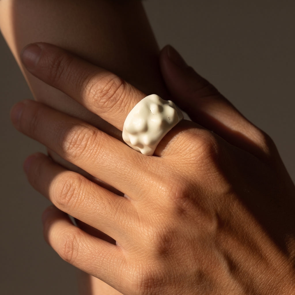 Erizo — anillo de porcelana blanca con textura nodular en mano con luz cálida