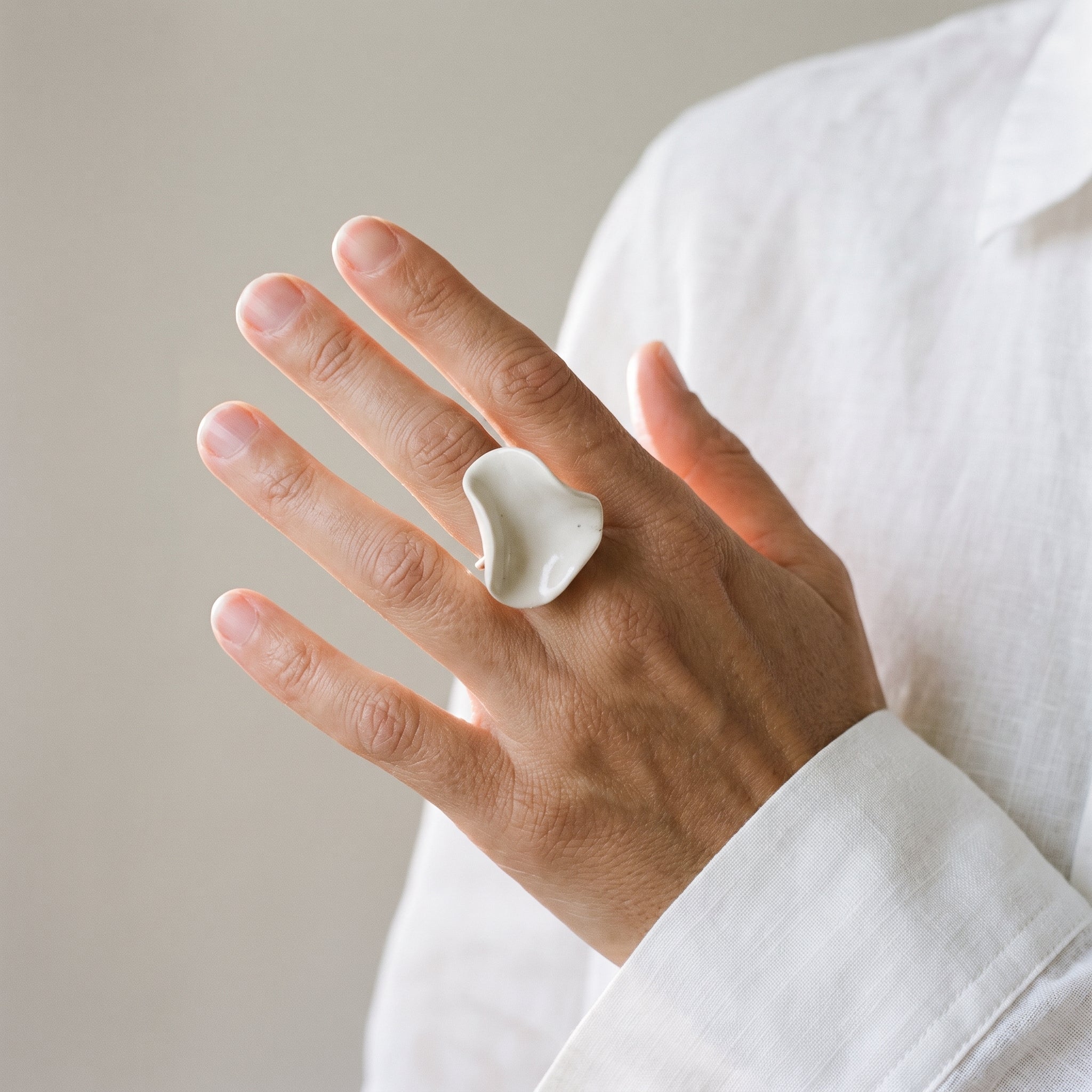 Pétalo Blanco — anillo de porcelana en mano con camisa blanca