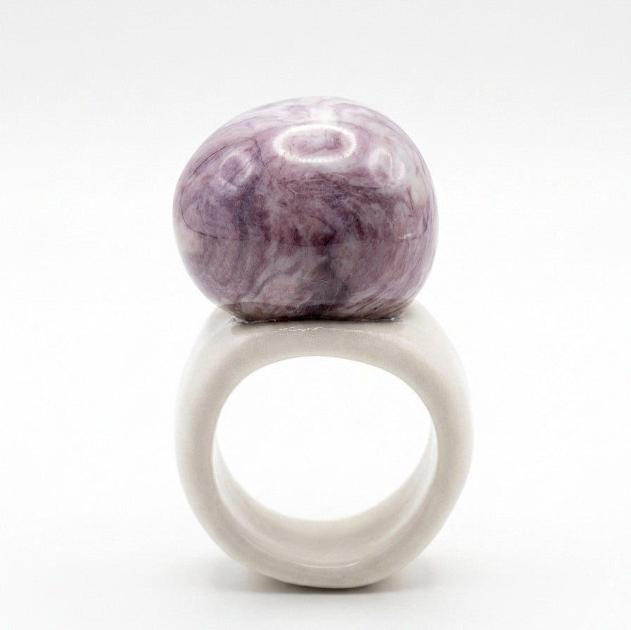 Trazo Malva — anillo de porcelana con cúpula esférica malva y aro ancho blanco mate, vista lateral sobre fondo blanco mostrando el volumen y la estructura