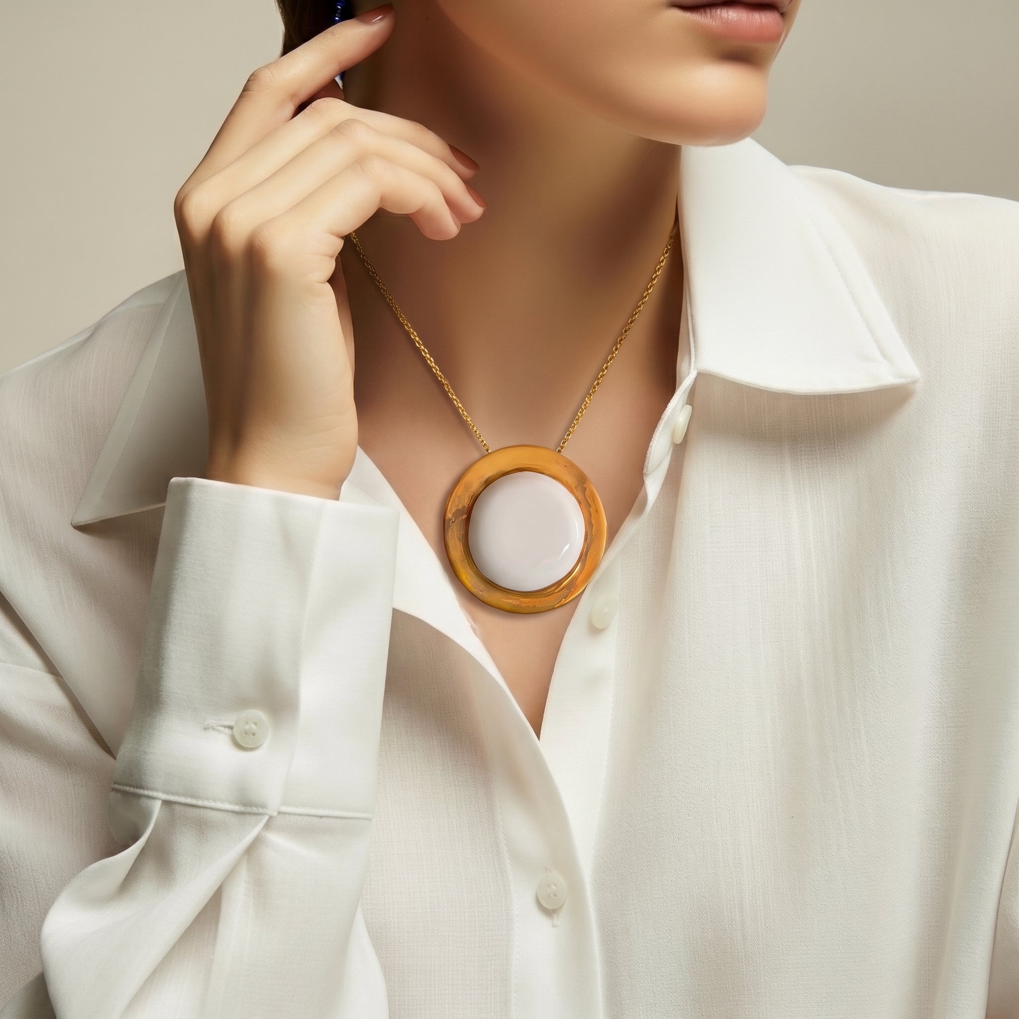 Eclipse Parcial colgante — disco de porcelana blanca con aro de oro en cuello de mujer con camisa lino blanca, fondo beige con luz suave lateral