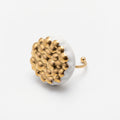 Maní Dorado — anillo de porcelana blanca con cúpula de esferas doradas sobre fondo blanco, vista lateral mostrando el volumen, el aro fino dorado con terminación en bola y el contraste blanco-oro