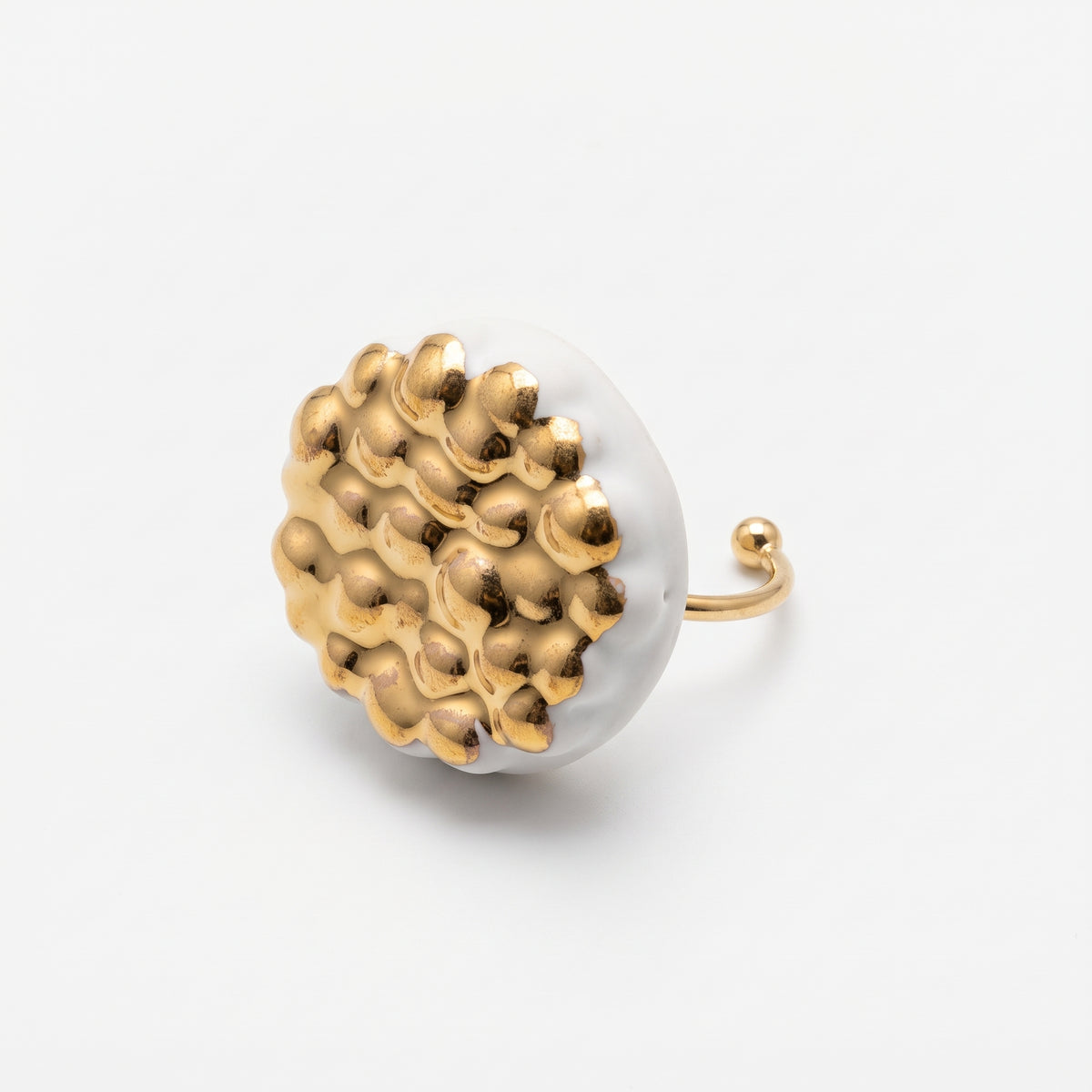 Maní Dorado — anillo de porcelana blanca con cúpula de esferas doradas sobre fondo blanco, vista lateral mostrando el volumen, el aro fino dorado con terminación en bola y el contraste blanco-oro