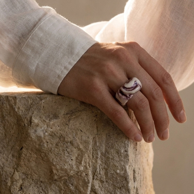 Petra Surco Lilac — anillo de porcelana marmolada lila en mano apoyada sobre piedra
