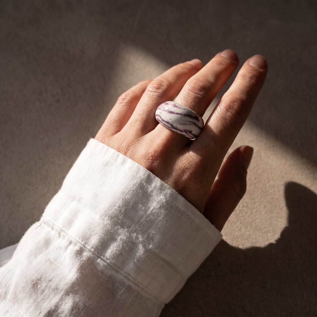 Petra Lilac — anillo de porcelana marmolada lila en mano con camisa blanca, luz solar