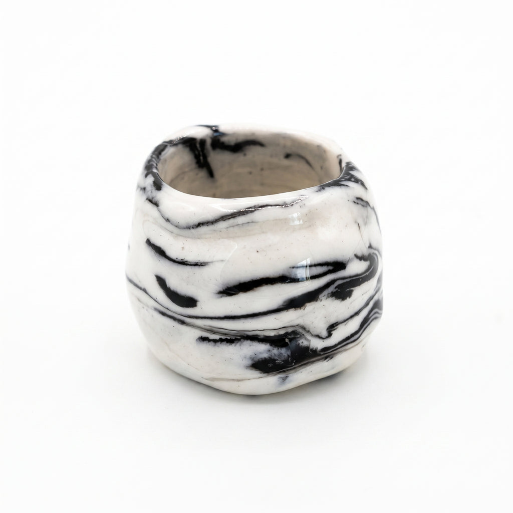 Petra Black — anillo de porcelana blanca con vetas negro intenso marmoladas, forma volumétrica orgánica, vista frontal sobre fondo blanco
