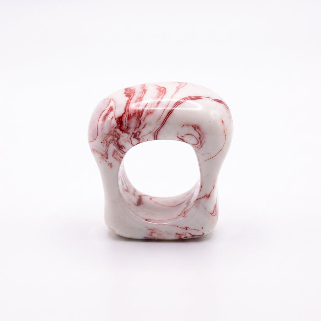Petra Coral — anillo de porcelana blanca con vetas coral-rojo marmoladas, forma ancha y orgánica, vista frontal sobre fondo blanco