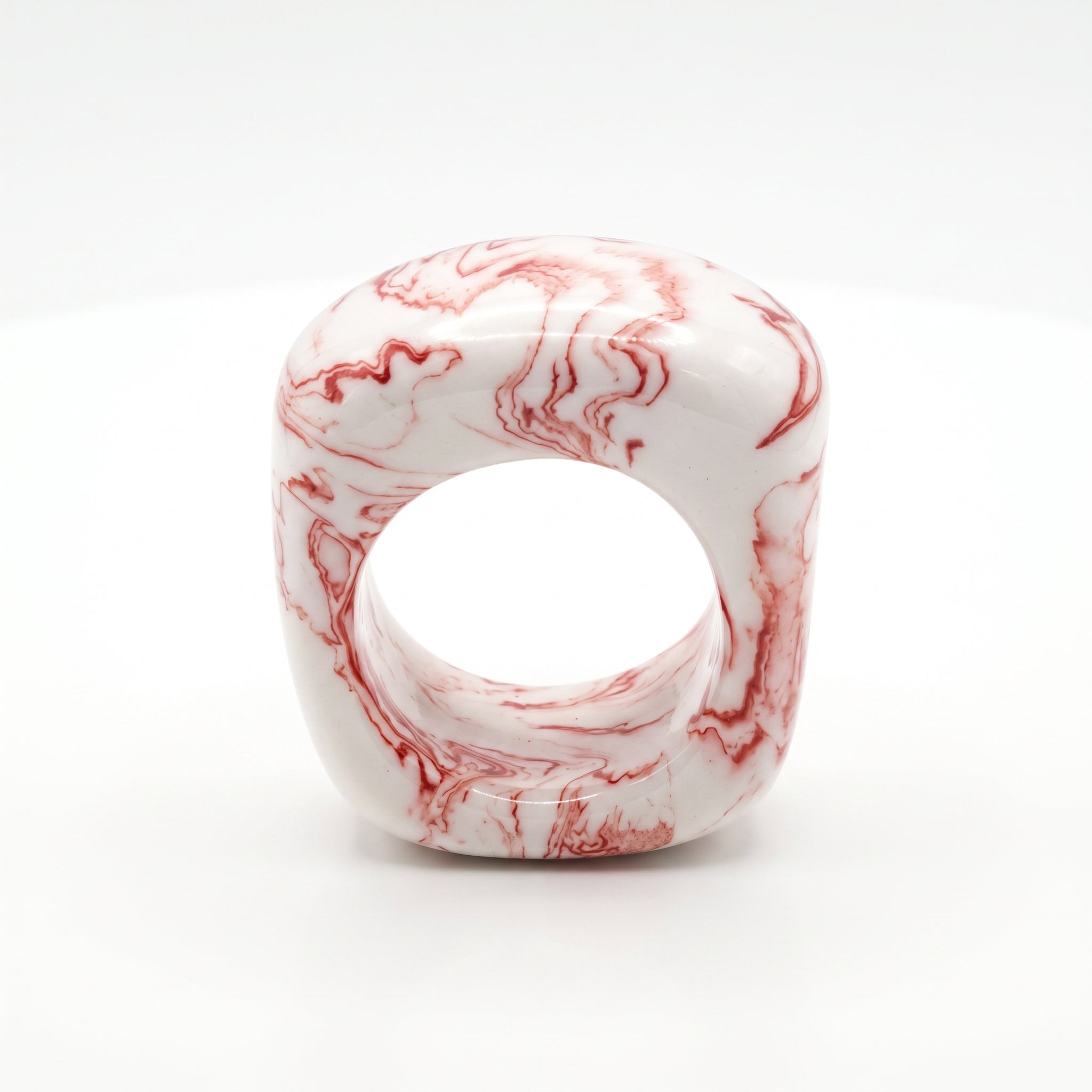 Petra Coral Small — anillo de porcelana blanca con vetas coral-rojo marmoladas a mano, forma cúbica redondeada, vista frontal sobre fondo blanco