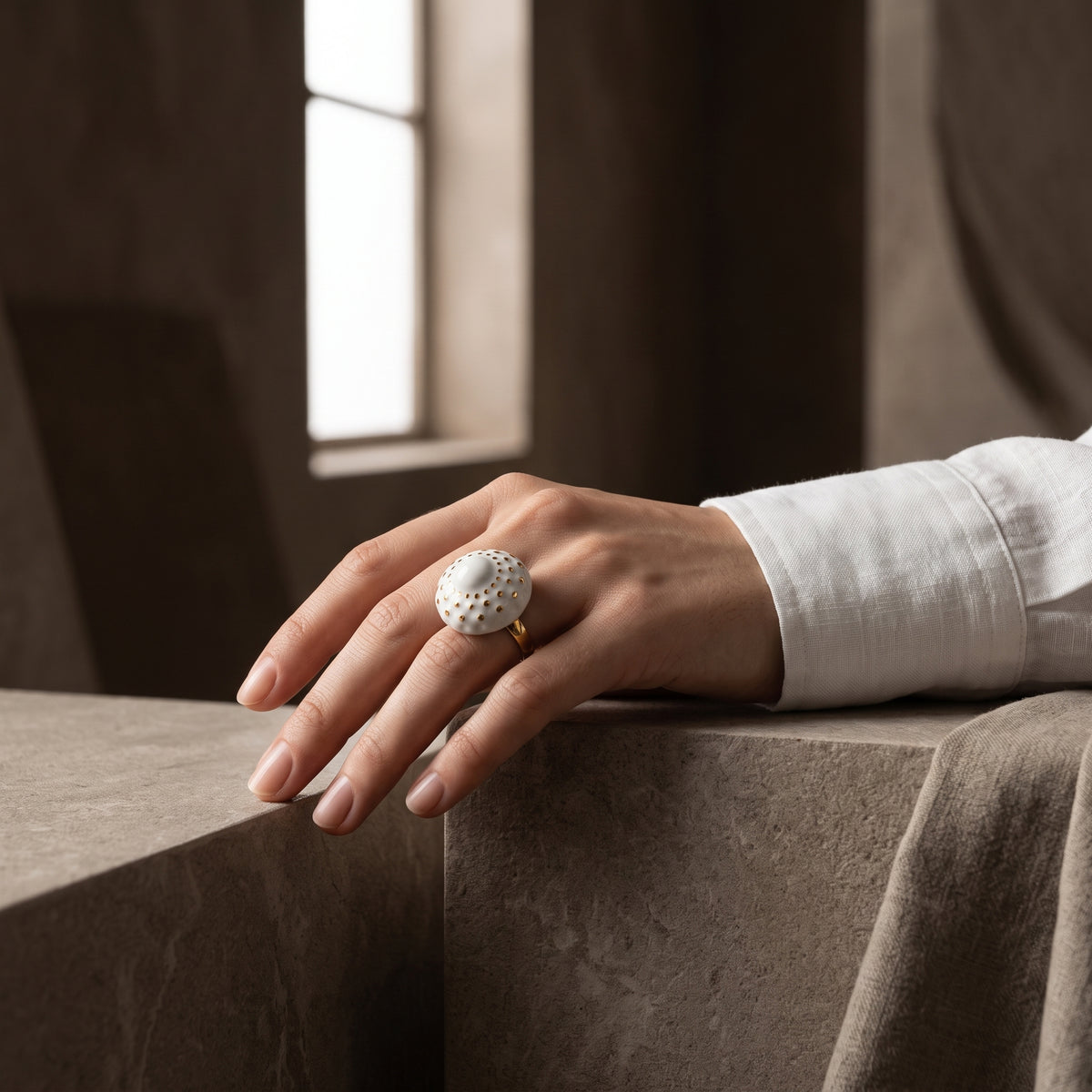 Girándola Blanco Oro S — anillo en mano masculina con camisa blanca de lino, dedos entrelazados, fondo beige neutro