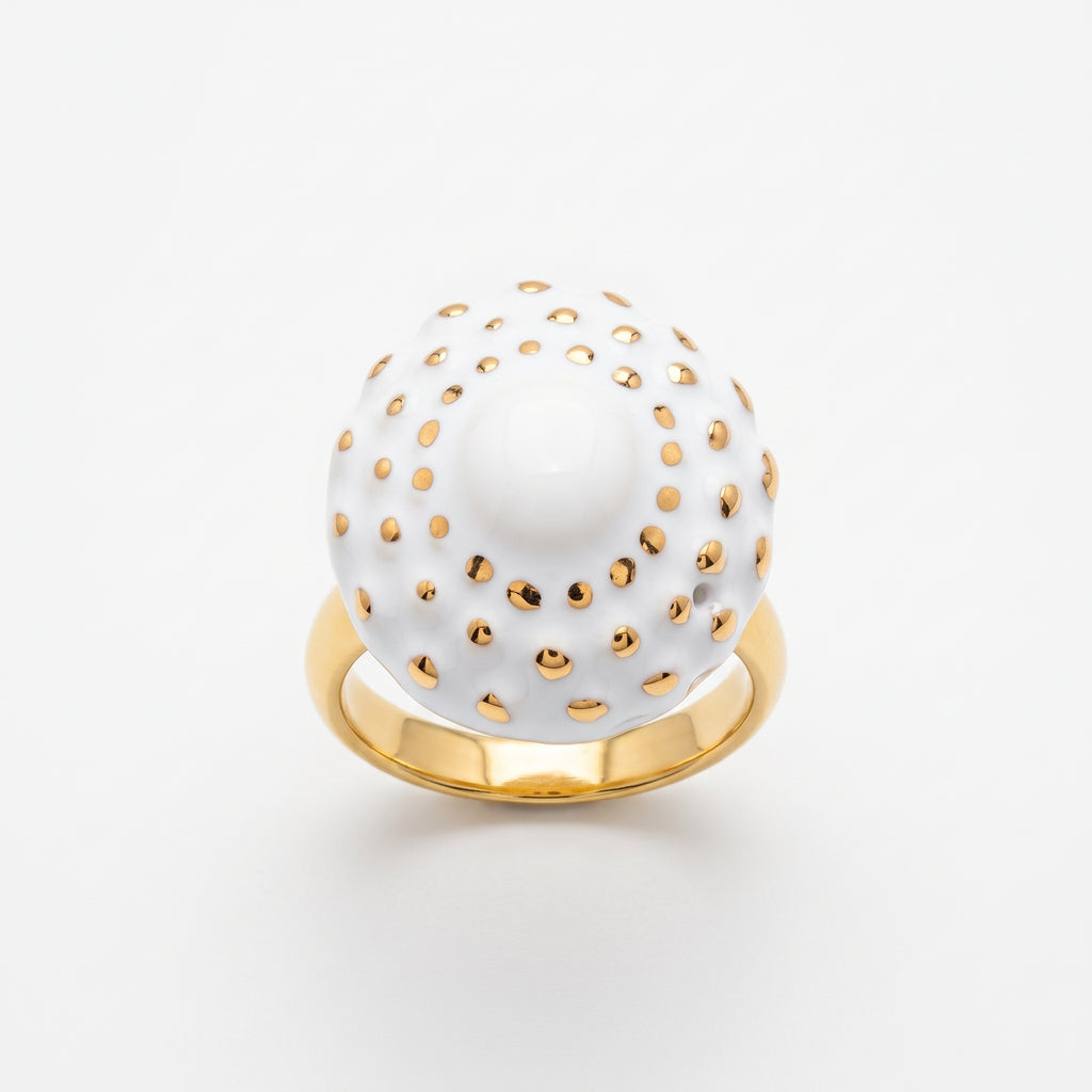 Girándola Blanco Oro S — anillo en dedo índice de mano femenina con camisa blanca, fondo beige cálido con luz lateral suave