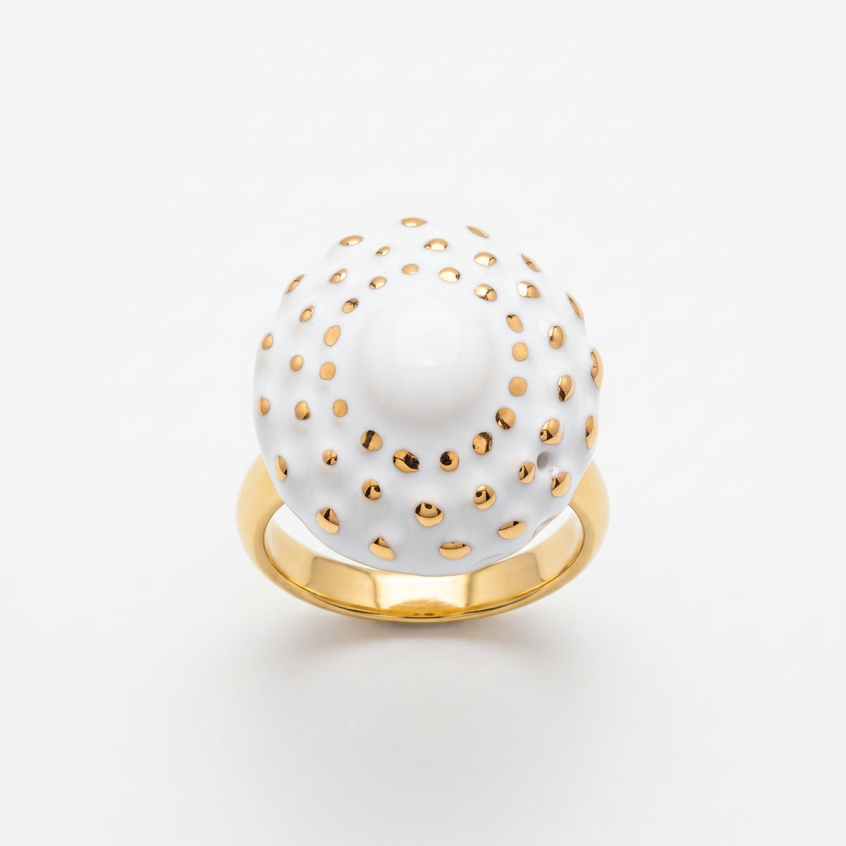 Girándola Blanco Oro S — anillo en dedo índice de mano femenina con camisa blanca, fondo beige cálido con luz lateral suave