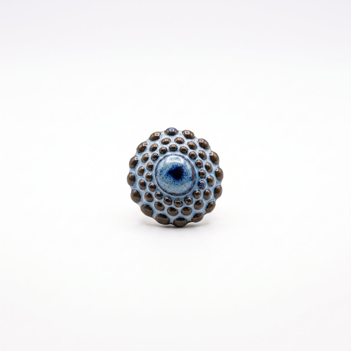 Girándola Azul Pizarra — anillo de porcelana con esfera de bultos en azul pizarra y puntos marrón oscuro sobre aro fino dorado con terminación en bola, vista lateral sobre fondo blanco