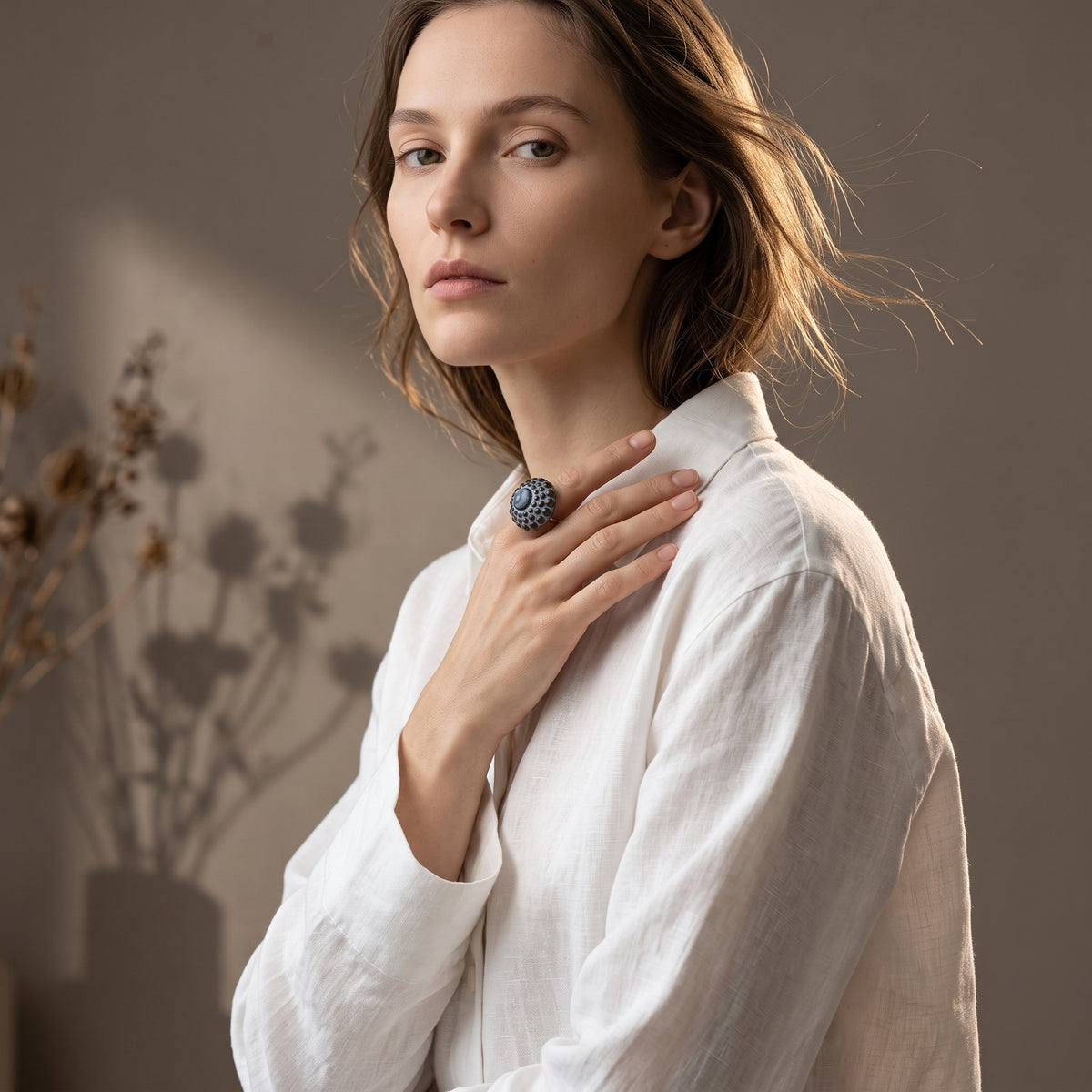 Girándola Azul Pizarra — anillo de porcelana azul pizarra en mano masculina con camisa lino sobre mesa de madera junto a cuencos cerámicos apilados, vista editorial