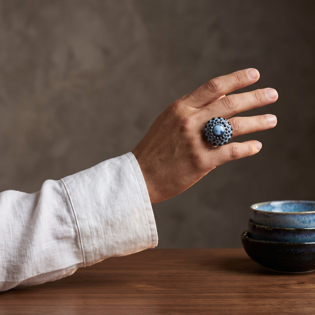 Girándola Azul Pizarra — anillo de porcelana con esfera de bultos azul pizarra y centro liso con ojo de índigo profundo, vista frontal sobre fondo blanco