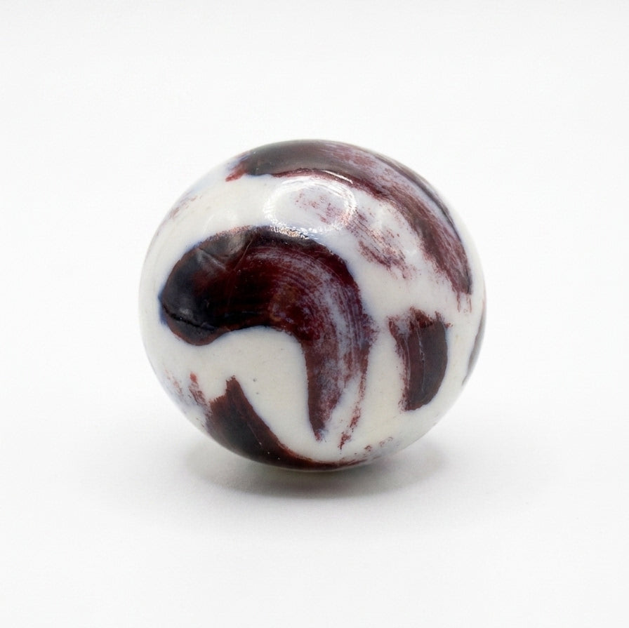 Trazo Lila — anillo de porcelana con cúpula esférica burdeos lila y aro ancho blanco mate en mano alzada con camisa blanca, fondo beige con luz solar lateral